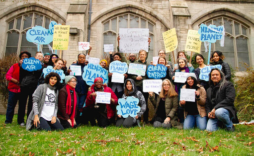 Grupo posando mientras sostiene carteles azules con llamados a tener aire limpio y un planeta saludable.