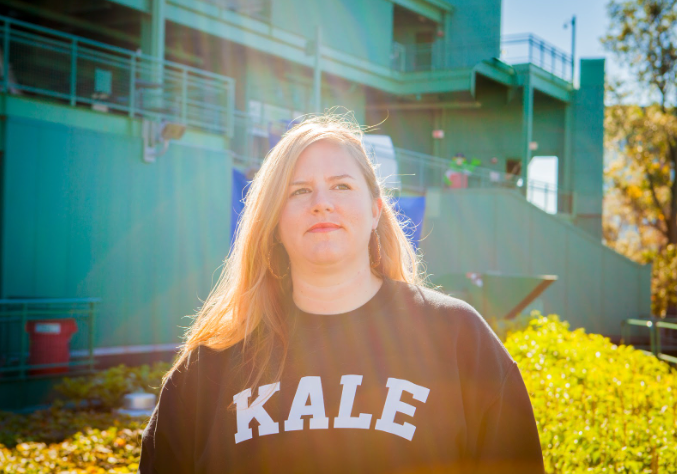 Headshot of a blonde woman, wearing a swetshirt that says Kale, on a very sunny day