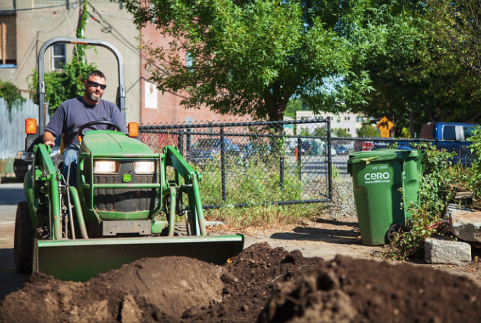 Man using a machine to mix soil in a raised bed garden