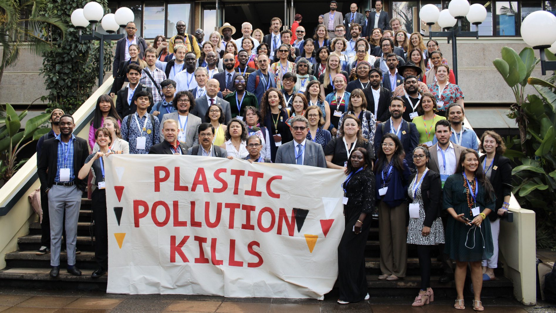 A delegação GAIA no INC3 segura uma serpentina que diz: A poluição por plásticos mata