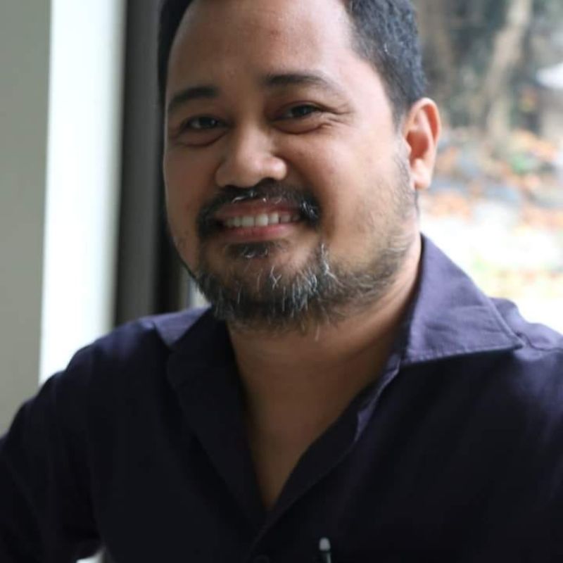 Headshot of asian man, wearing a dark blue shirt and smiling at camera.
