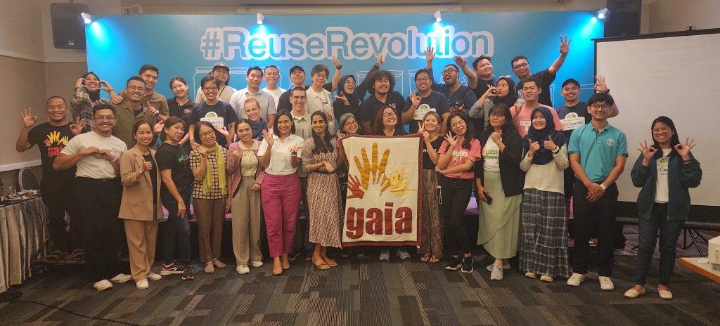 A group of people smiling and posing for a photo in front of the Reuse Revolution banner.