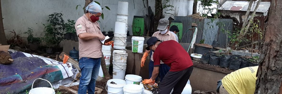 Three informal waste workers in are collecting organic waste in white pails at a composting and organic garden in Bandung