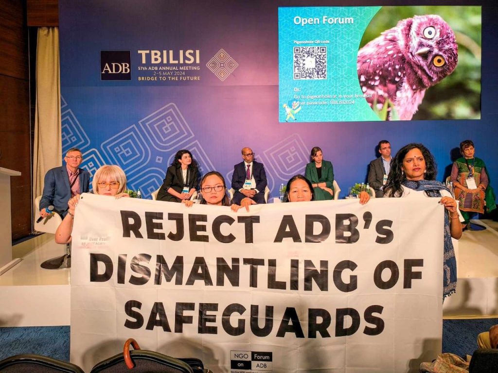a group of people holding a banner with the text that says, "Reject ADB's Dismantling of Safeguards".